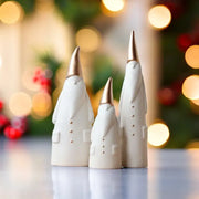 Three white and gold ceramic santa claus figurines with button details for christmas living room decor