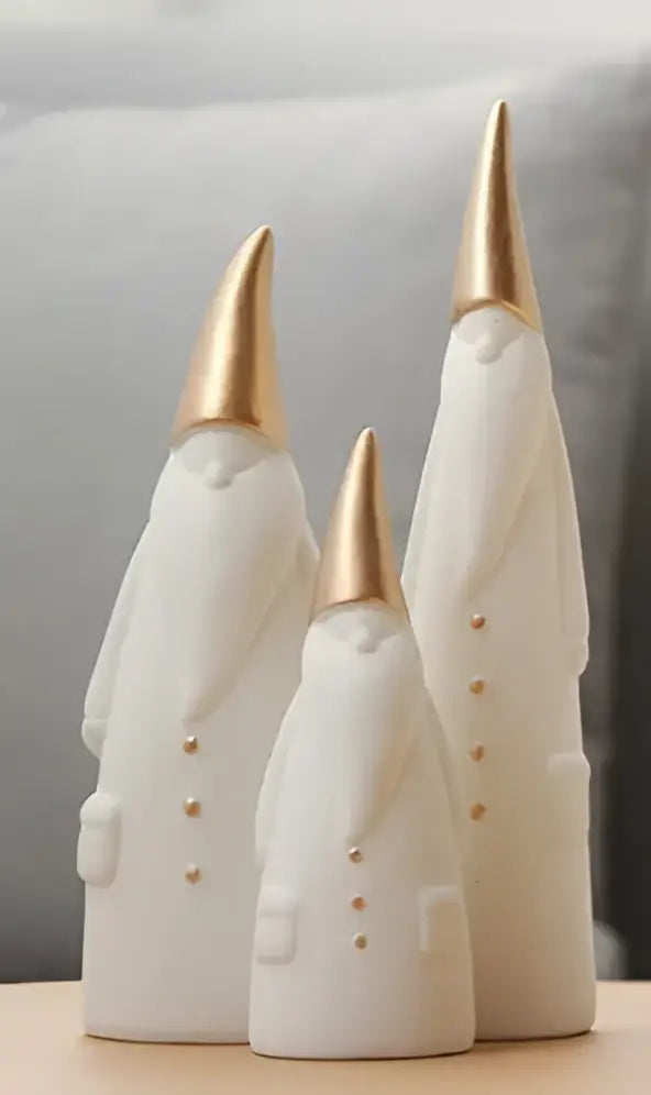 Three white and gold ceramic santa claus figurines with gold-tipped hats and button details for christmas decor