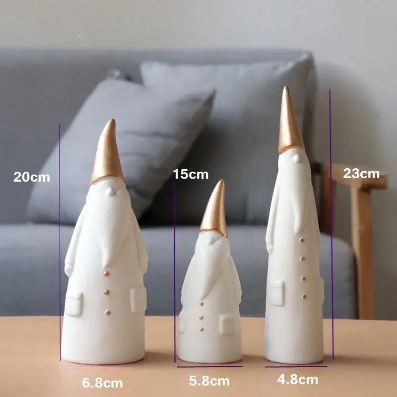 Three white and gold ceramic santa claus figurines with gold-tipped hats and subtle button details for christmas decor
