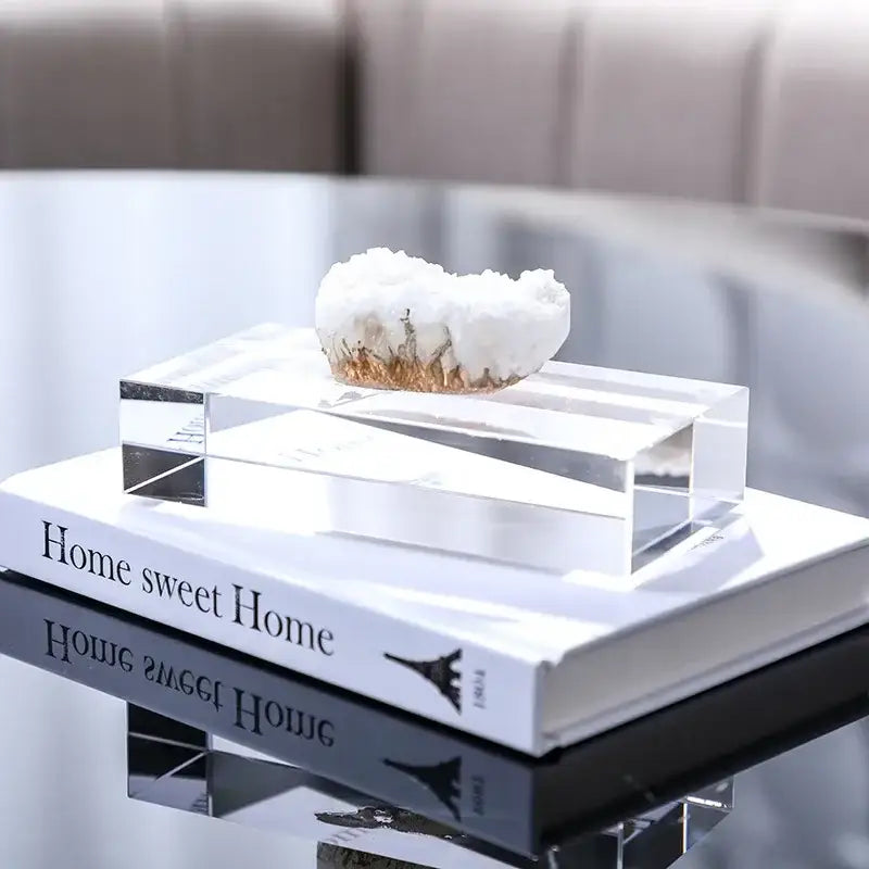 A white and gold crystal coralline ornament with crystalline geode details displayed on a clear acrylic block
