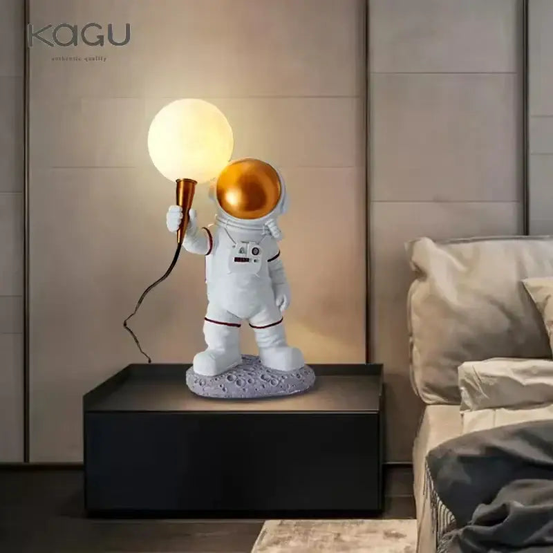 White and gold decorbites astronaut moon lamp with glowing bulb standing on moon planet table for bedroom light