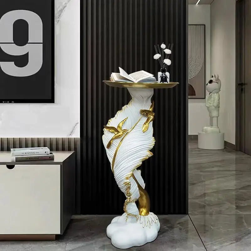 White and gold sculptural console table with feather floor decoration design holding an open book and vase