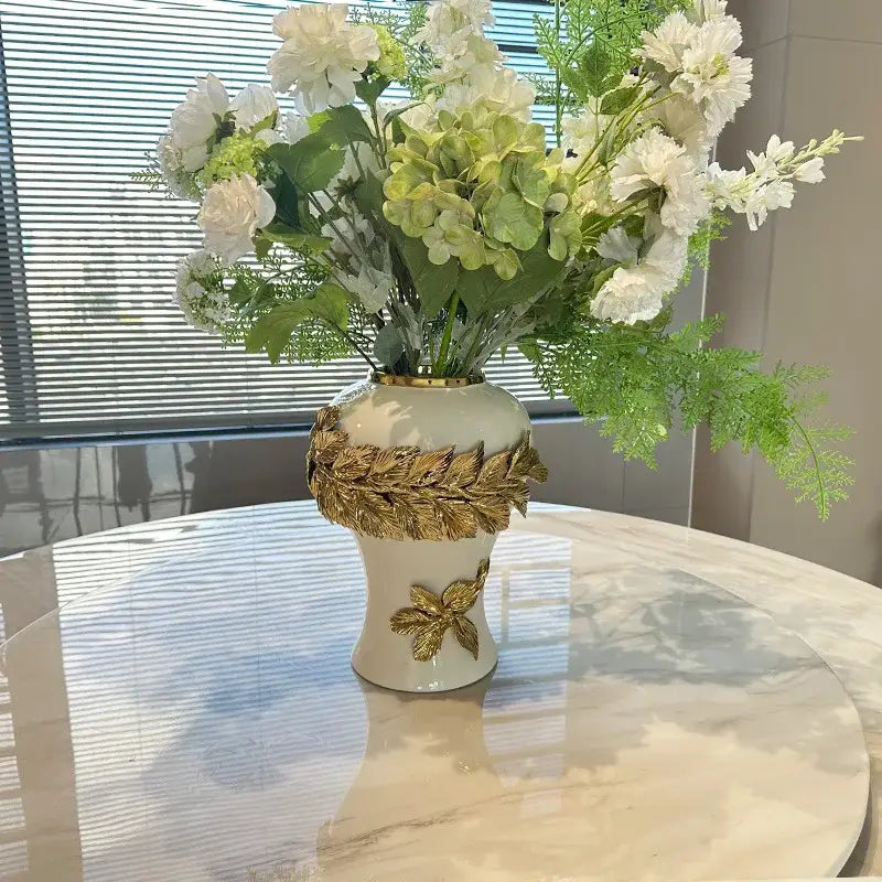 Cream-colored leaves ceramic flower vase with decorbites golden leaves and golden rim holding white flowers for living room decor
