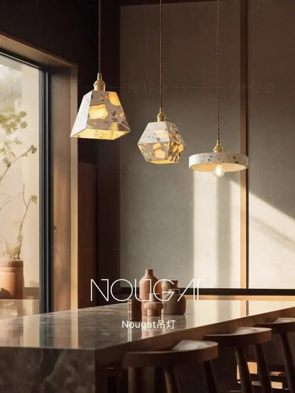 White and gold terrazzo cement marble chandelier with brass accents hangs above a dining table for decorbites table lamp decor