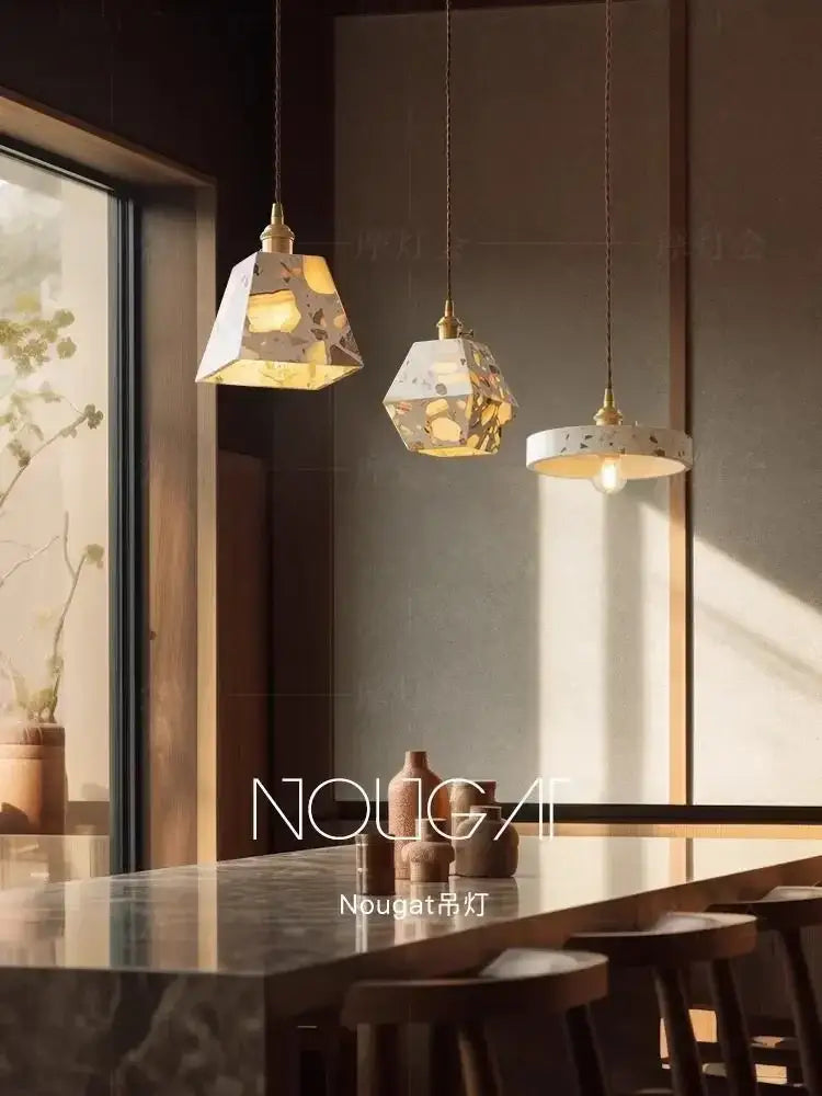White and gold terrazzo cement marble chandelier with brass accents hangs above a dining table for decorbites table lamp decor