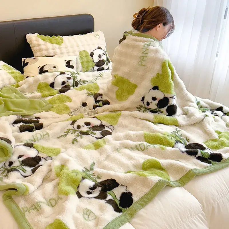 A cream cartoon printed faux rabbit plush blanket with black and white pandas and green leaf decorbites design