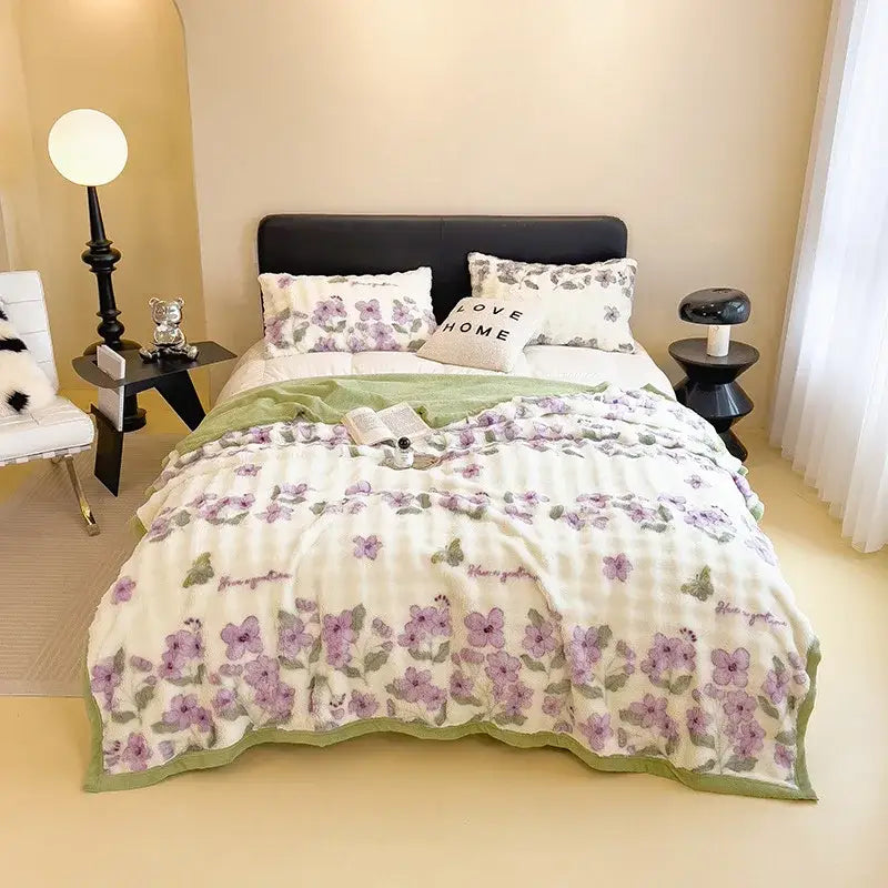A cream-colored quilt with purple floral pattern and green trim on a decorbites cartoon printed faux rabbit plush blanket