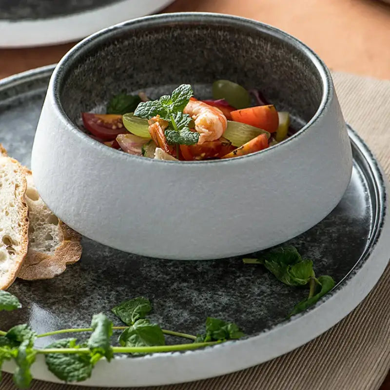 A matte white ceramic bowl with speckled dark gray rim filled with vegetables and shrimp from decorbites ice cracked glaze set