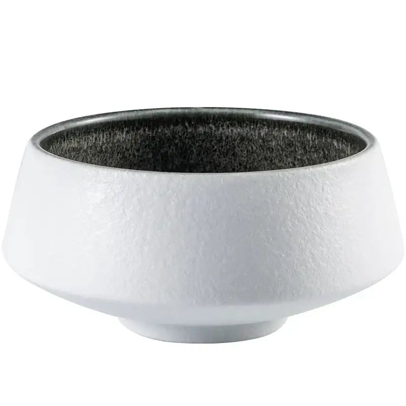 White ceramic bowl with textured exterior and speckled black interior featuring ice cracked glaze decorbites design
