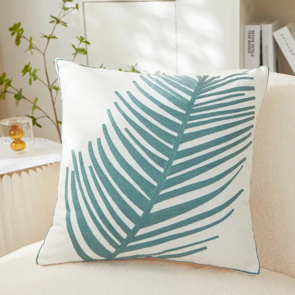 White pillow cover with teal embroidered leaf design ideal as an embroidered leaf pillow for living room decor