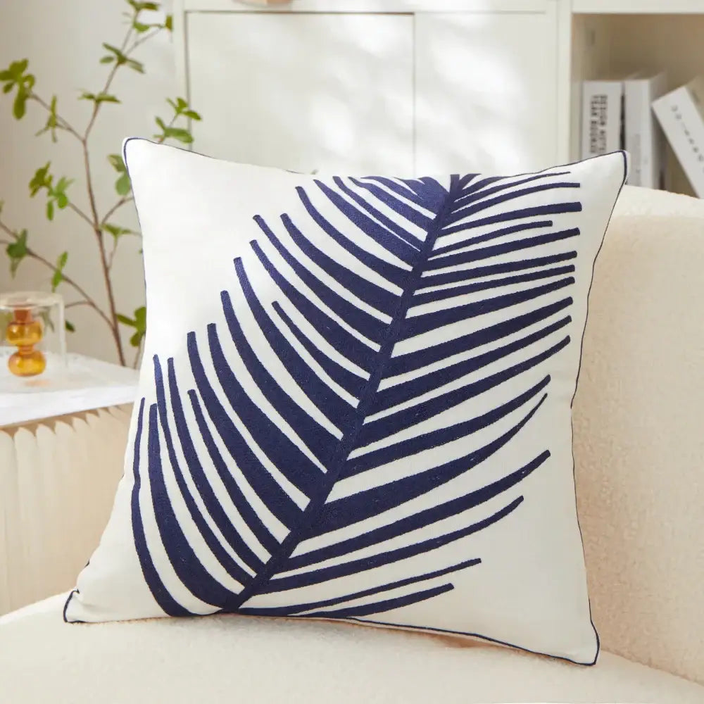 White cushion pillow cover with bold navy blue embroidered leaf design for living room decor