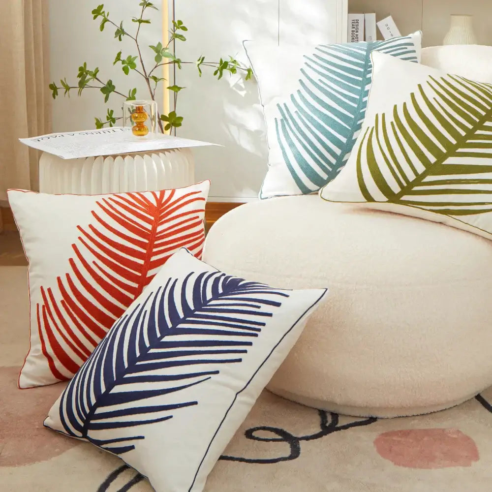 White throw pillow cover with bold embroidered leaf prints in red navy teal and olive green for living room decor