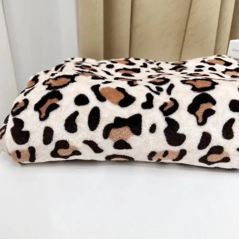 A cream-colored fleece throw with soft texture and bold black and tan leopard print warm decorbites leopard print design