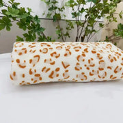 A soft rolled-up white fleece blanket with bold orange leopard print decorbites leopard print warm throw
