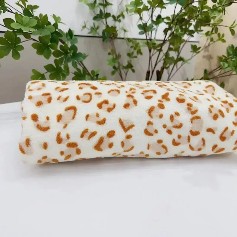 A soft rolled-up white fleece blanket with bold orange leopard print decorbites leopard print warm throw