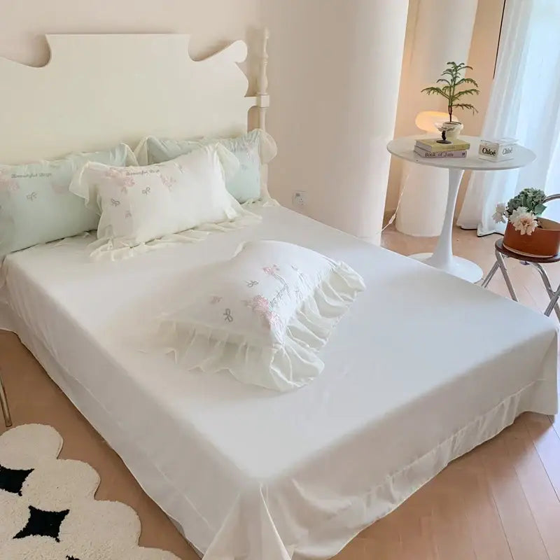 White ruffled pillow with delicate pink flowers embroidery in a 4pcs flowers embroidery bedding set