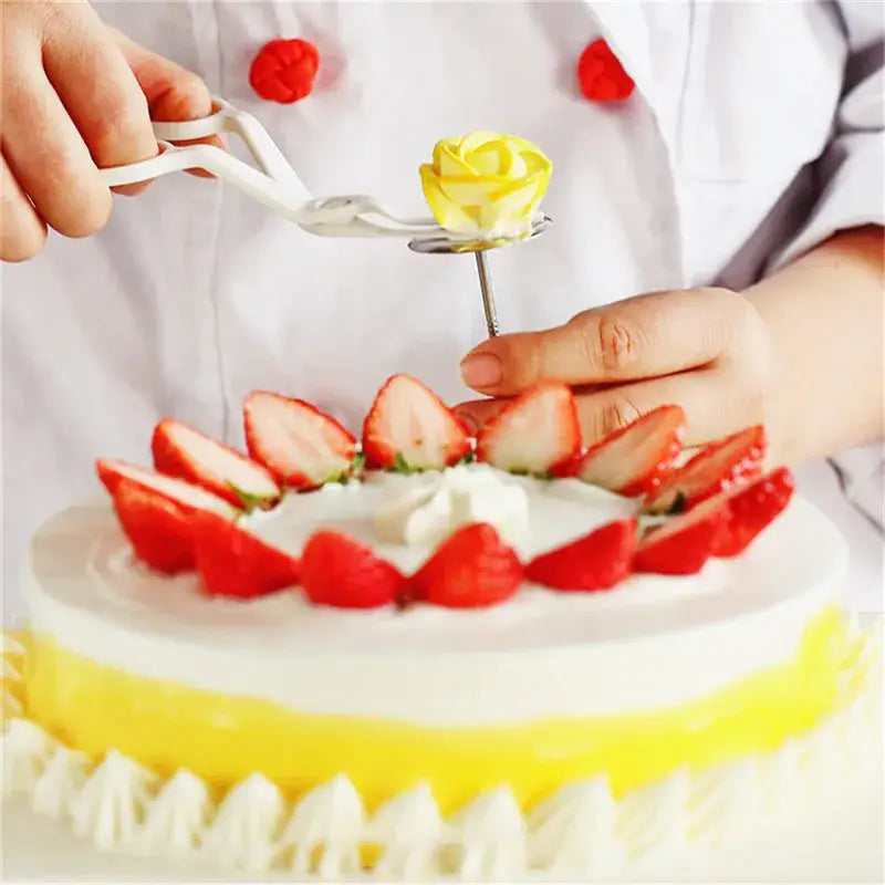 A delicate yellow icing rose is placed on a cake using a white and pink decorbites cream flower scissors set for decorating