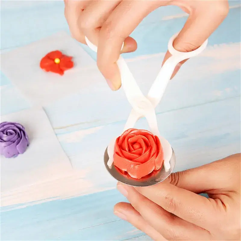 White plastic cream flower scissors set with metal base holding orange frosting rose for cake decorating decorbites cream flower