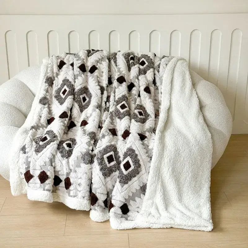 A plush white and pink geometric jacquard taff velvet bedroom throw blanket with textured gray and brown pattern