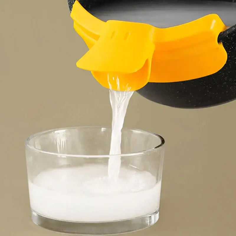 Bright yellow silicone decorbites duck beak funnel attached to a black pot for easy controlled pouring