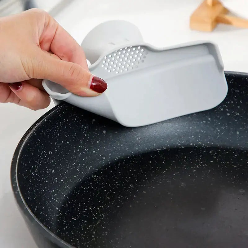 Gray silicone pot scraper with perforated surface and ergonomic handle for white and yellow decorbites duck beak funnel use