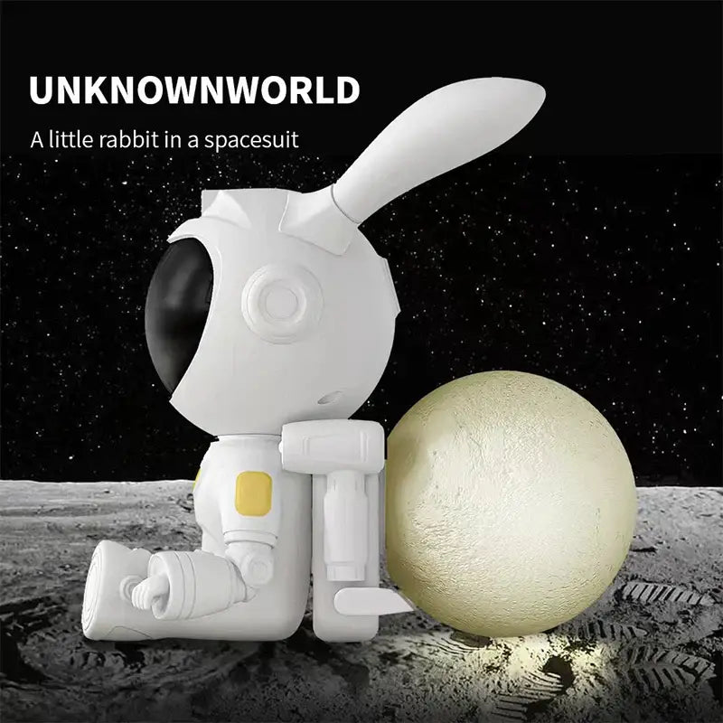 White and yellow galaxy bunny astronaut night light figurine with black visor sitting beside glowing moon lamp decorbites galaxy bunny