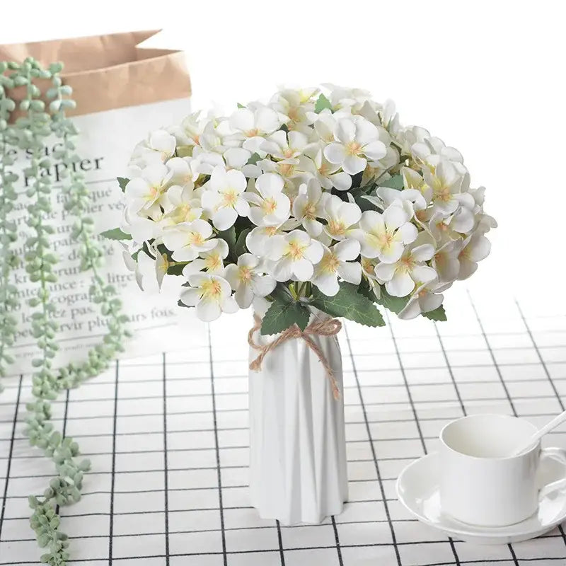 White ceramic vase with vertical ridges holding a white begonia silk flower bouquet for living room decor