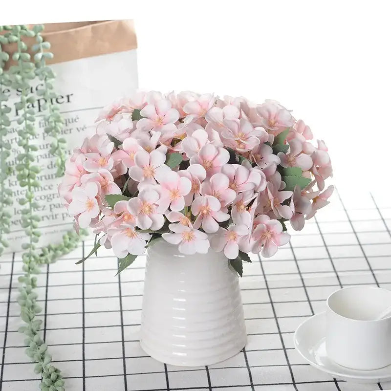 Delicate white begonia silk flower bouquet with pink and yellow artificial flowers in a white ceramic vase decor