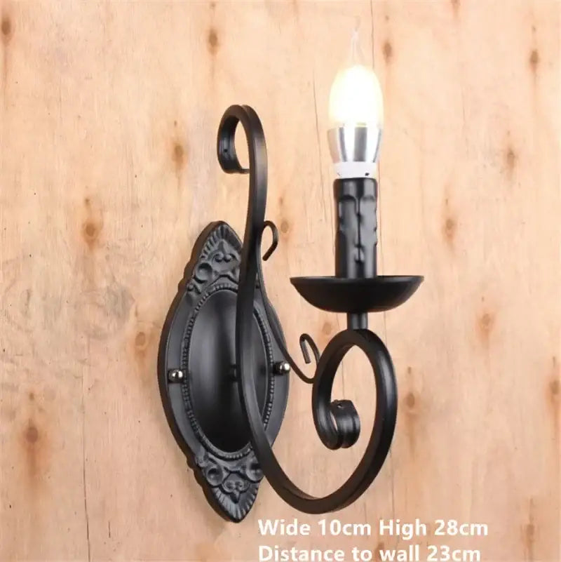 Black wrought iron wall sconce with ornate scrollwork and candle bulb complementing decorbites black white metal chandelier with crystal pendants