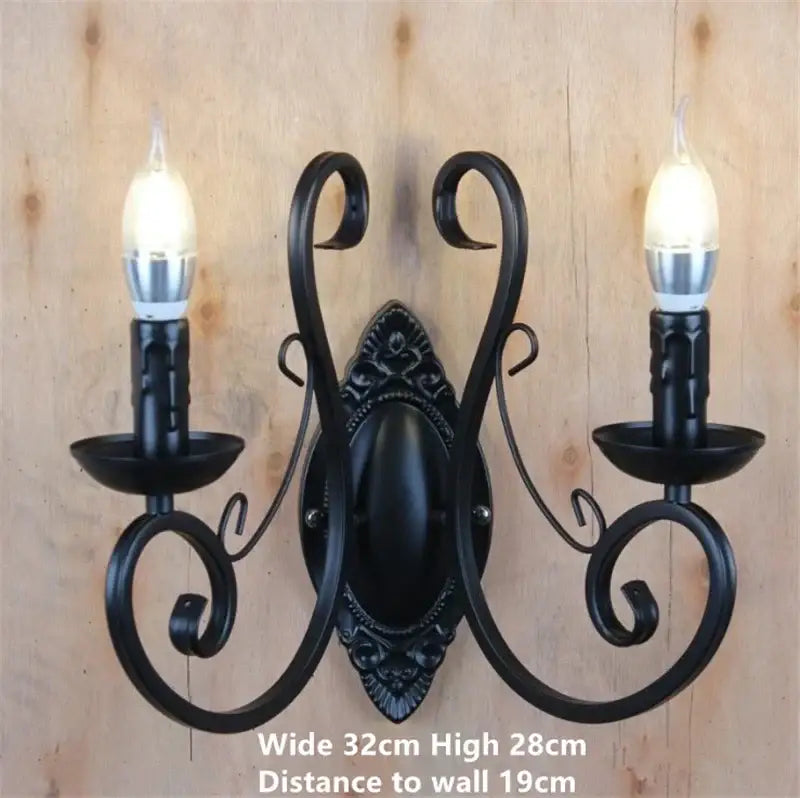 Black wrought iron two-light wall sconce with ornate scrollwork and candle-style bulbs in black white metal decorbites style