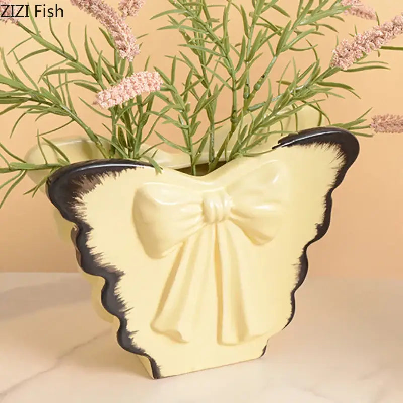 Cream-colored decorbites butterfly ceramic vase with black trim and raised pink bow for living room decor