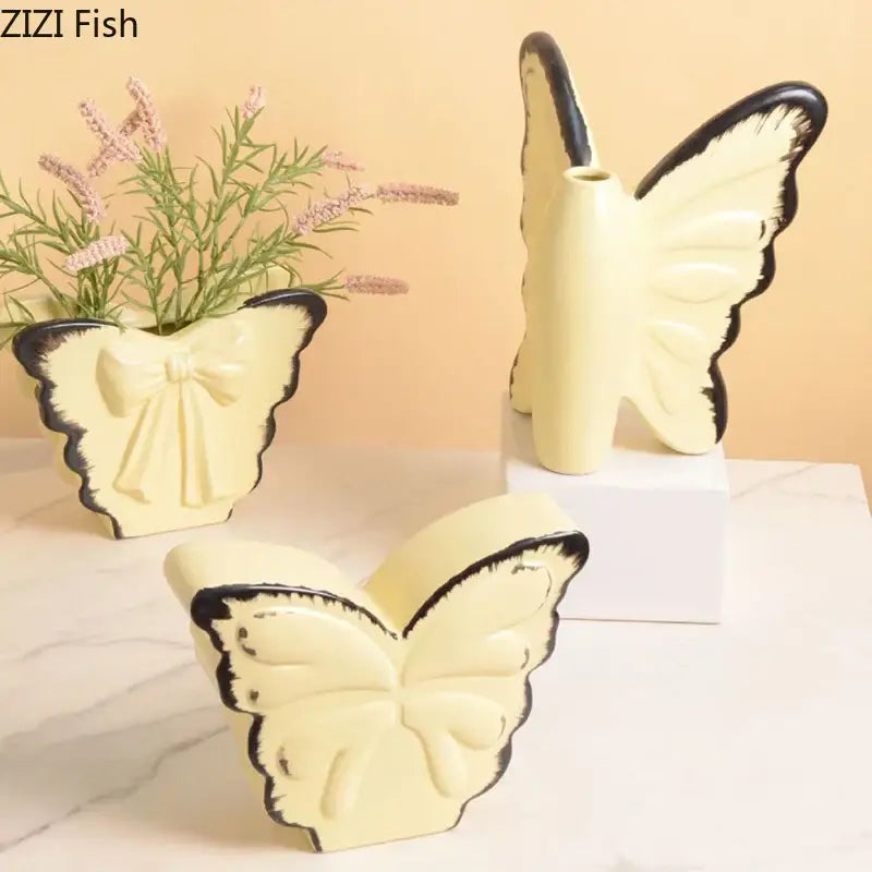 White butterfly ceramic vase by decorbites with cream color black-trimmed wings and central plant opening for decor