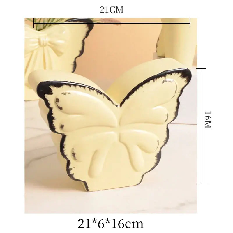 Cream-colored decorbites butterfly ceramic vase with black outlined wings and pink bow for living room decor