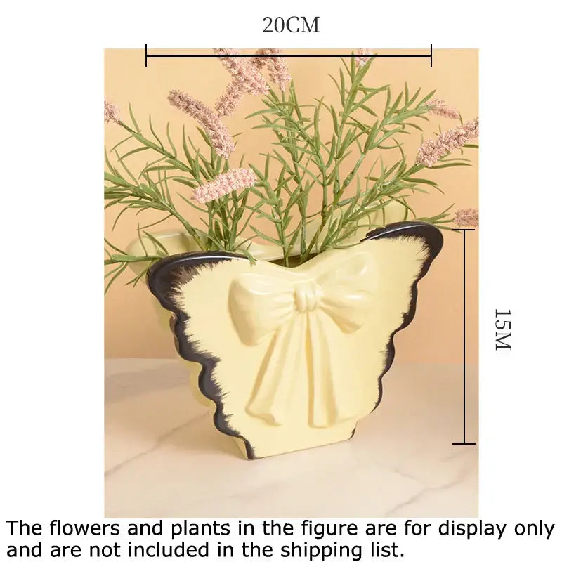 Cream-colored decorbites butterfly ceramic vase with black-edged wings and pink bow for living room decor