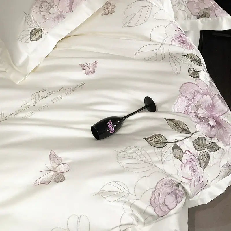 Black champagne flute with pink girl logo beside white butterfly flowers embroidery egyptian cotton bedroom bedding set
