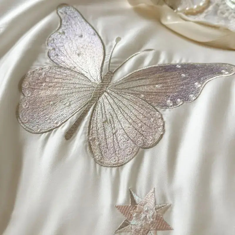 A white butterfly lace ruffles bedding set featuring a delicately embroidered silver butterfly appliqué with iridescent wings
