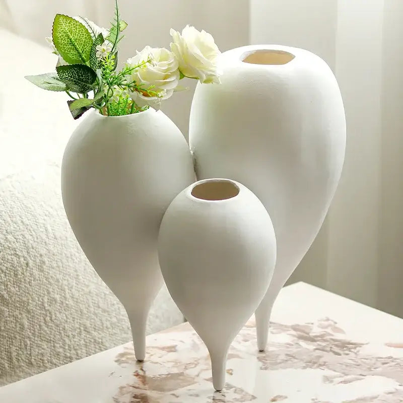Three elegant white ceramic balloon geometric vases with slender legs in a geometric vase trio for living room decor