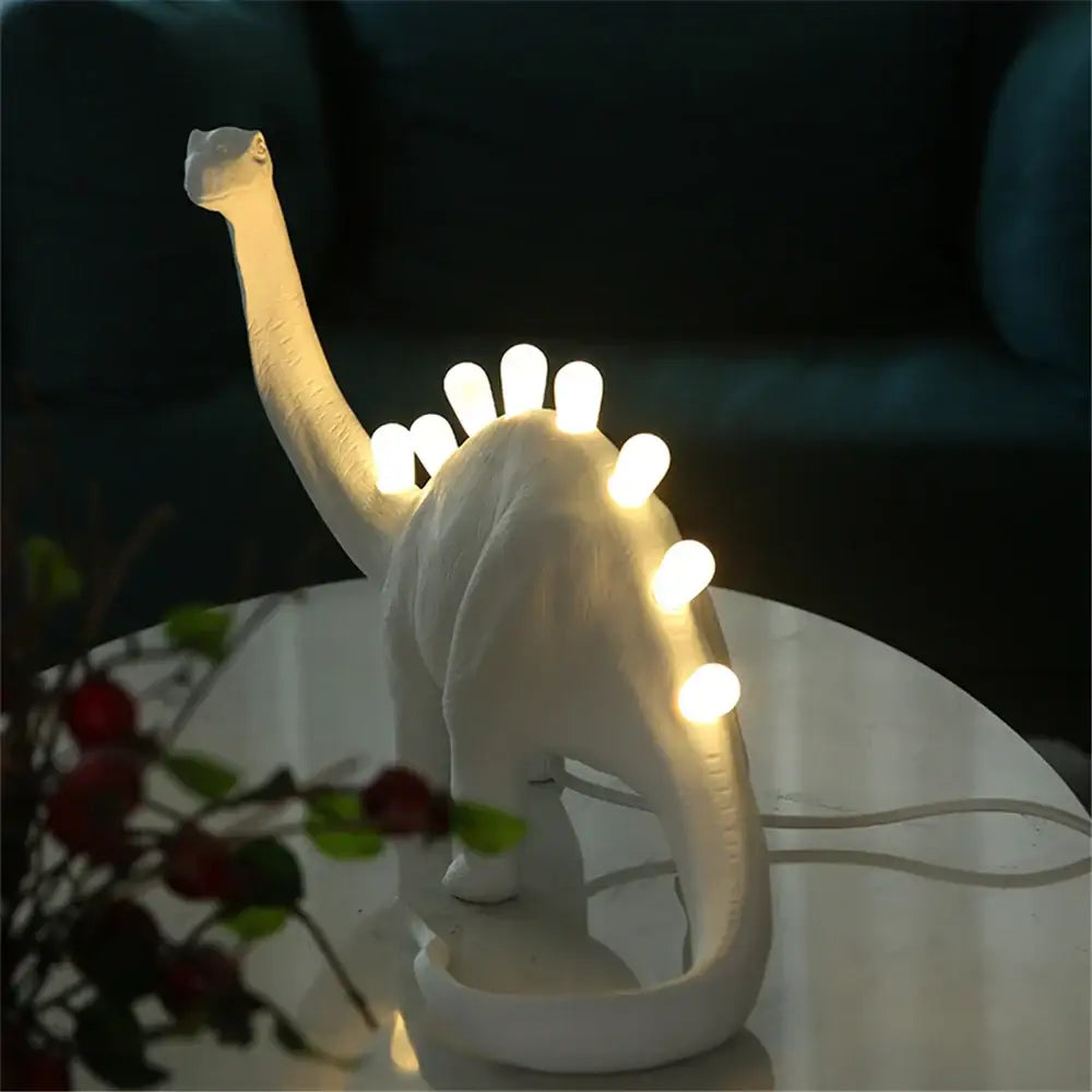 White ceramic dino led desk lamp with glowing lights along its back ideal for bedroom lighting decorbites dino led