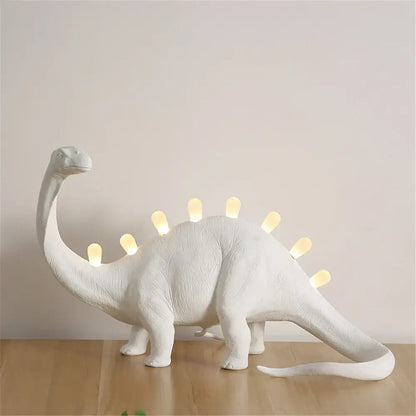 White ceramic dino led desk lamp with glowing yellow lights along its back for bedroom decorbites dino led lighting