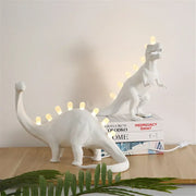 White ceramic dino led desk lamp with glowing led lights along its back and tail for bedroom decorbites dino led lighting