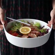 White ceramic double handle salad bowl by decorbites filled with greens tomatoes grilled meat and lemon slice for dining use