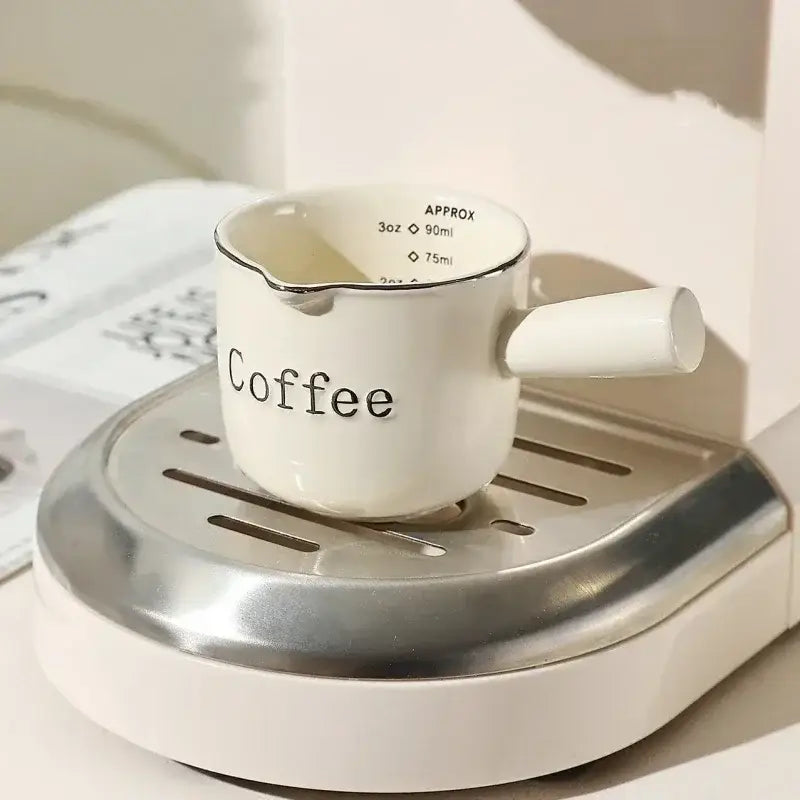 White ceramic espresso measuring cup with black coffee lettering and silver rim for decorbites milk pitcher use