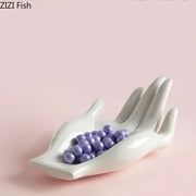 White ceramic hand-shaped fruit plate tray holding purple beads for living room decor