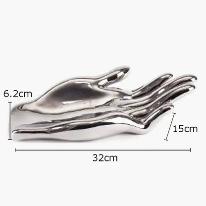 Shiny silver metallic sculpture of an open hand serving as a decorative fruit plate tray for living room decor