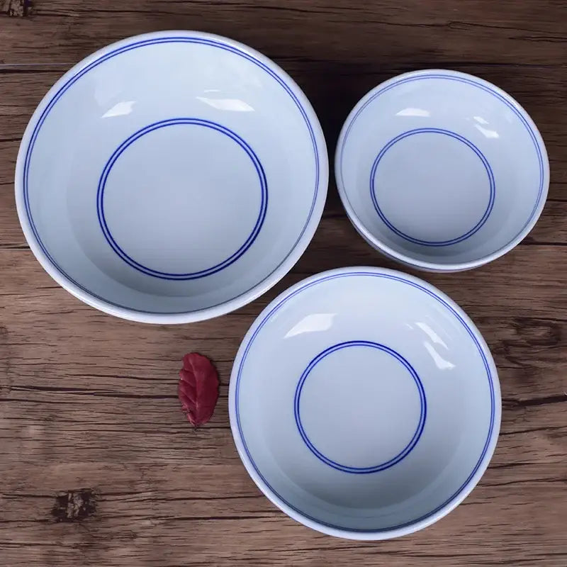Three white ceramic noodle bowls with blue rim and concentric circles by decorbites on wooden dining tableware