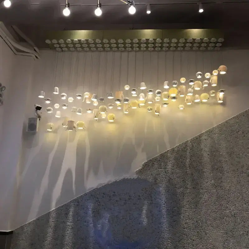 A modern sculptural wall installation of white ceramic led pendant lights shaped like teapots and mugs for kitchen decorbites ceramic led