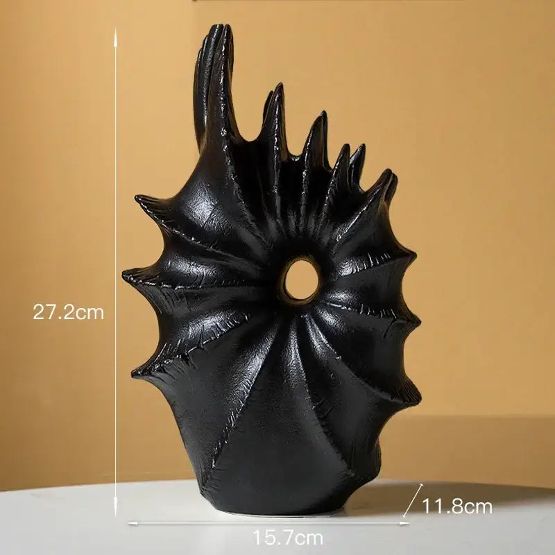 Black glossy resin sculpture with radial spiky design and central hole complementing conch shape ceramic vase for artificial flower arrangements