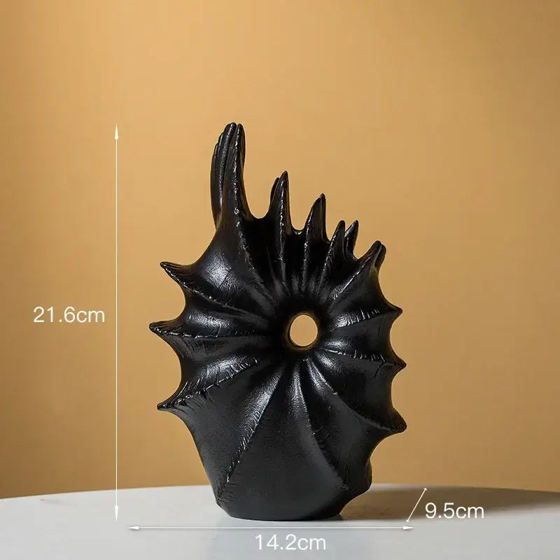 Black glossy resin sculpture with spiky radial design and central hole complementing ceramic vase for artificial flower arrangements