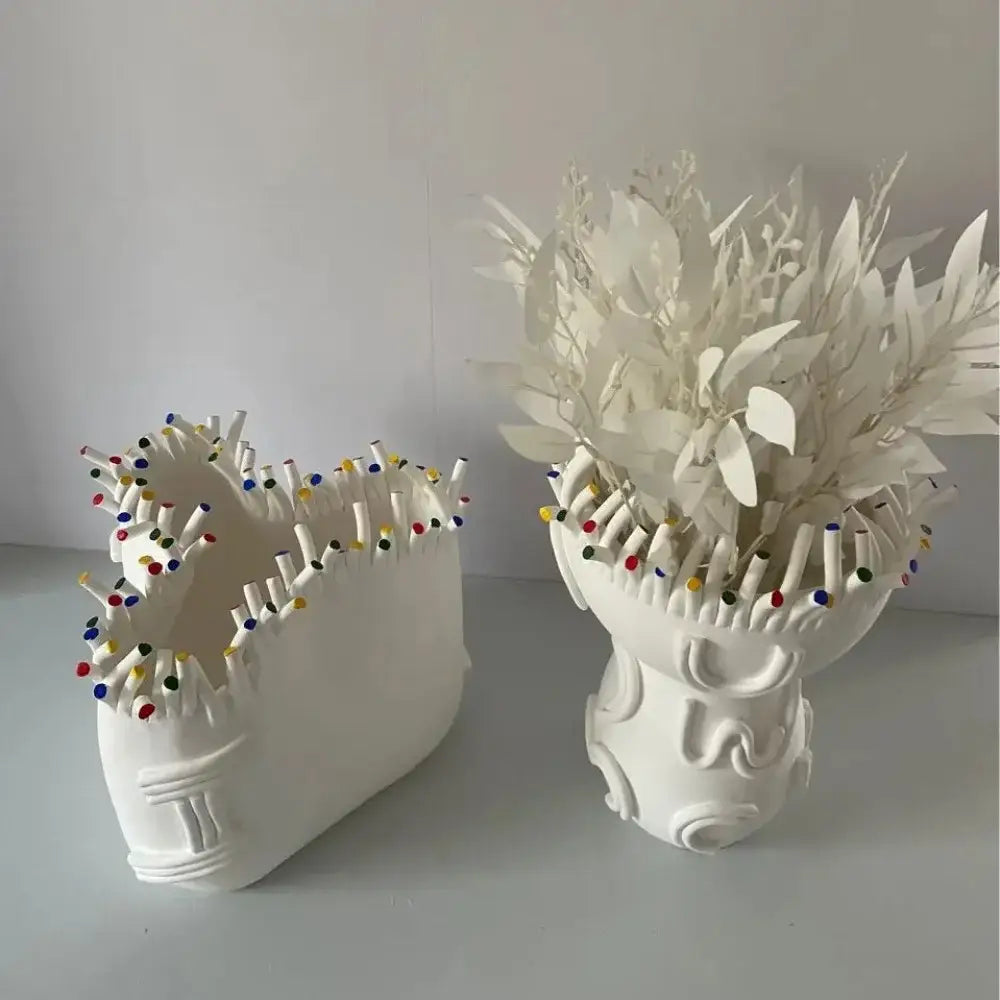 White ceramic flower pot vase with intricate coral shapes filled with white artificial foliage for living room decor