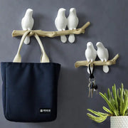 White decorbites bird resin hanger with white ceramic bird wall hooks mounted on a natural wood branch